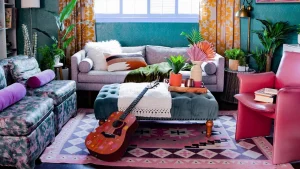 70s style. guitar leaning on blue table. white vase with pink flowers.